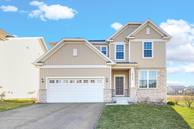 craftsman house featuring stone siding, driveway, a garage, and a front lawn