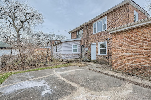 rear view of house featuring brick siding, fence, and a patio