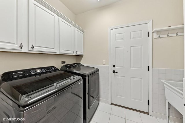 21827 W Riviera Ct, Ivanhoe, IL 60060 - laundry room with cabinet space, washer and dryer, tile walls, a wainscoted wall, and light tile patterned flooring