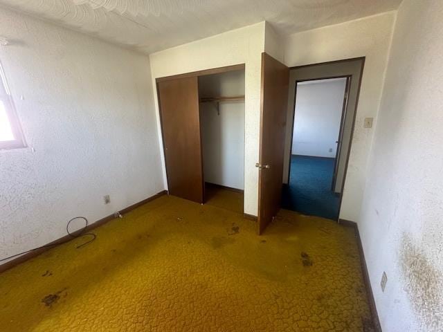 unfurnished bedroom featuring carpet, a closet, and baseboards