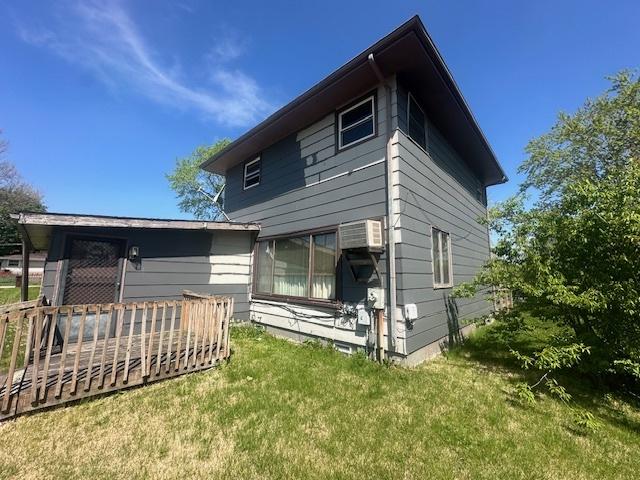back of house featuring a yard, a wooden deck, and a wall mounted air conditioner