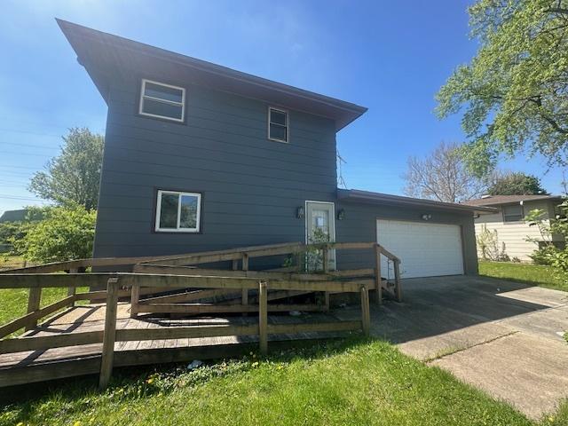 back of property with a deck, a garage, and driveway