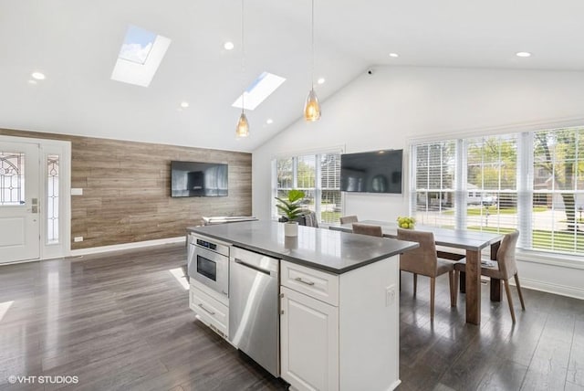 kitchen with high vaulted ceiling, dark countertops, open floor plan, stainless steel dishwasher, and wooden walls