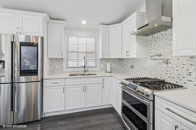 kitchen featuring stainless steel appliances, wall chimney exhaust hood, a sink, white cabinets, and light countertops