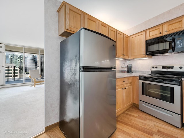 kitchen with stainless steel appliances, light countertops, and light wood finished floors