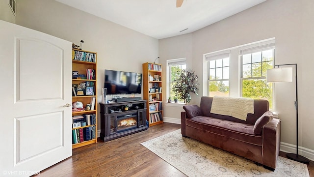 living area featuring wood finished floors, baseboards, and ceiling fan