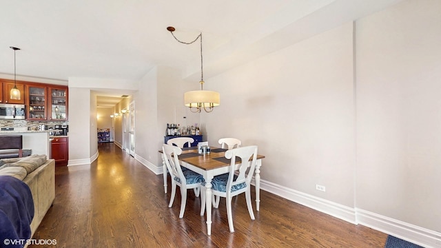 dining space featuring baseboards, dark wood finished floors, and a chandelier