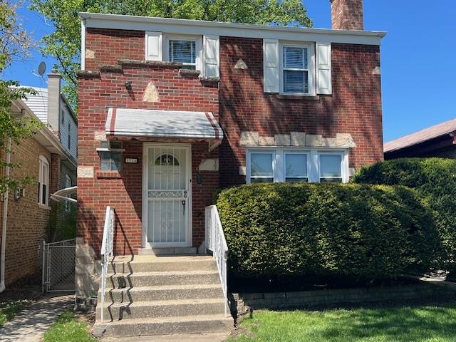 view of front of house featuring a chimney and brick siding