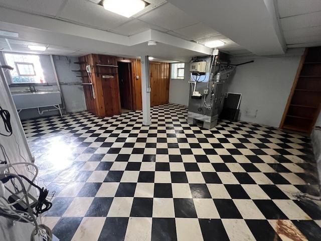 basement with heating unit, plenty of natural light, tile patterned floors, and a sink