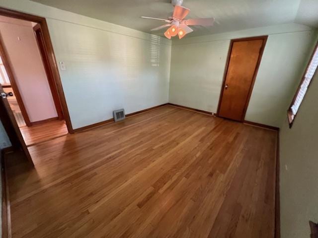 spare room featuring wood finished floors, a ceiling fan, and baseboards