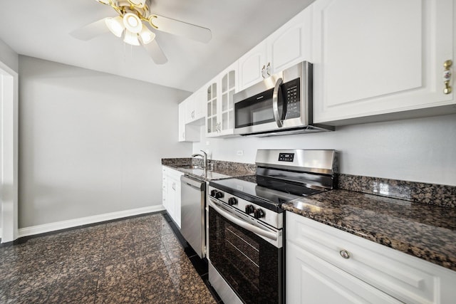kitchen with stainless steel appliances, granite floors, baseboards, white cabinets, and dark stone counters