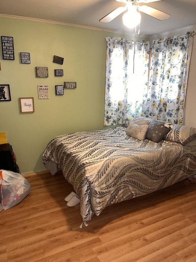 bedroom featuring wood finished floors, crown molding, baseboards, and ceiling fan