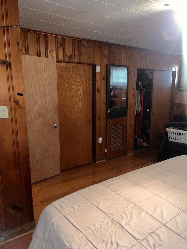 bedroom featuring wood finished floors and wooden walls