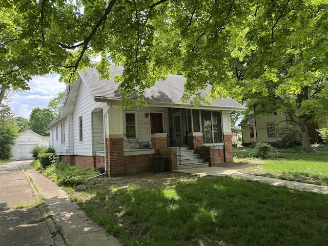 544 W Orleans St, Paxton, IL 60957 - view of front of property with brick siding, a sunroom, roof with shingles, a detached garage, and a front lawn