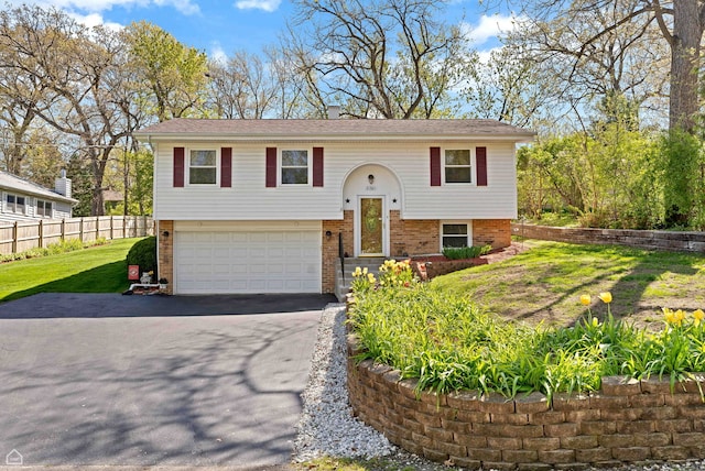 split foyer home featuring an attached garage, driveway, and brick siding