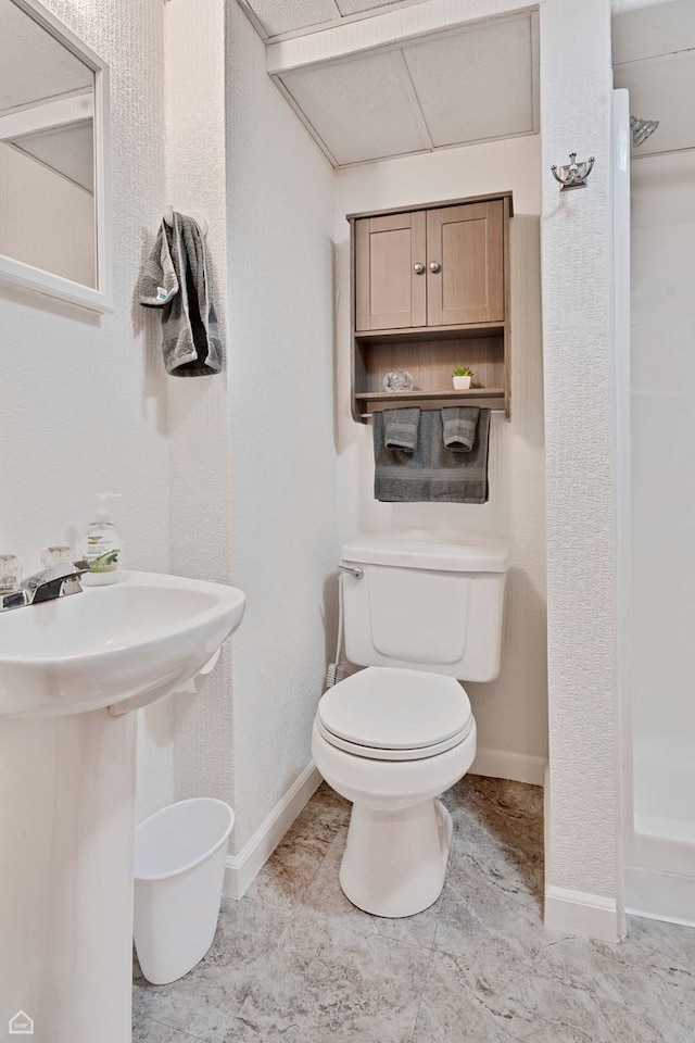 full bathroom featuring toilet, a shower stall, and baseboards