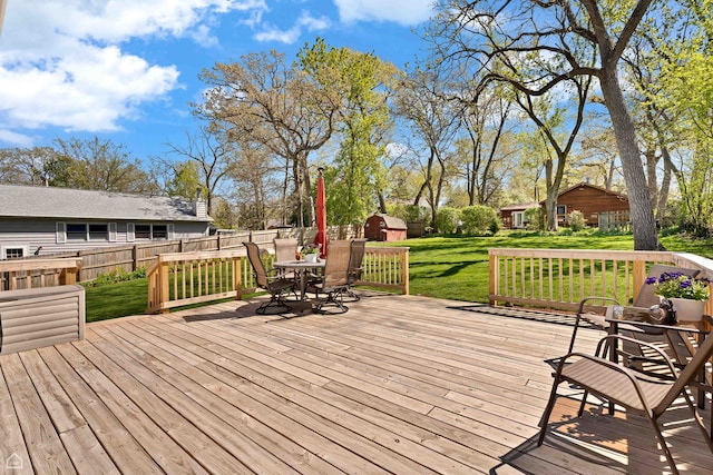 wooden terrace featuring outdoor dining space, a shed, and an outdoor structure