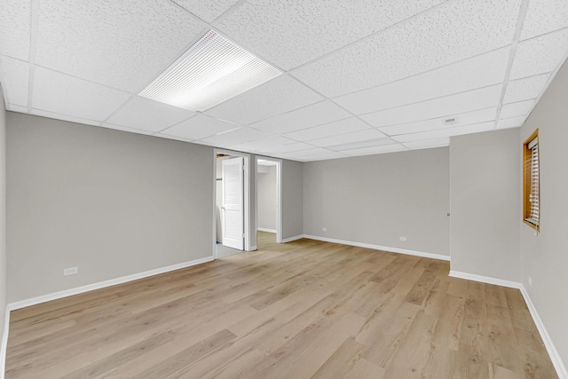 finished basement with light wood-style flooring, baseboards, and a drop ceiling