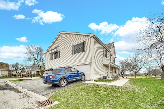 view of home's exterior with a lawn, asphalt driveway, an attached garage, and central AC