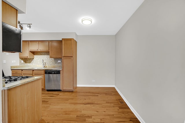 kitchen featuring dishwasher, light wood-style floors, stovetop, light countertops, and a sink