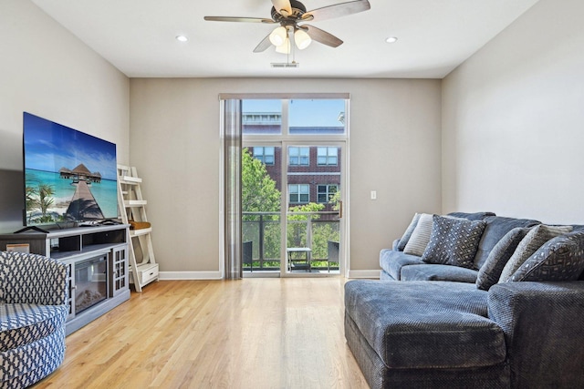 living area with light wood-type flooring, healthy amount of natural light, baseboards, ceiling fan, and recessed lighting