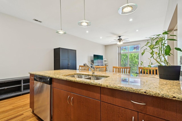 kitchen featuring stainless steel dishwasher, a sink, pendant lighting, light stone counters, and recessed lighting