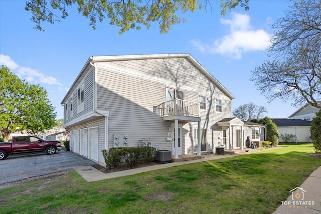642 Gray Ct Unit 0, Wheeling, IL 60090 - rear view of house with a balcony, an attached garage, central AC, a lawn, and asphalt driveway