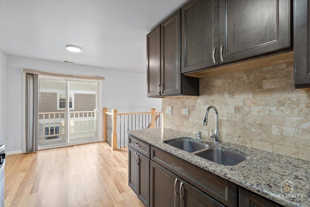 642 Gray Ct Unit 0, Wheeling, IL 60090 - kitchen featuring a sink, decorative backsplash, light wood-type flooring, dark brown cabinetry, and light stone countertops