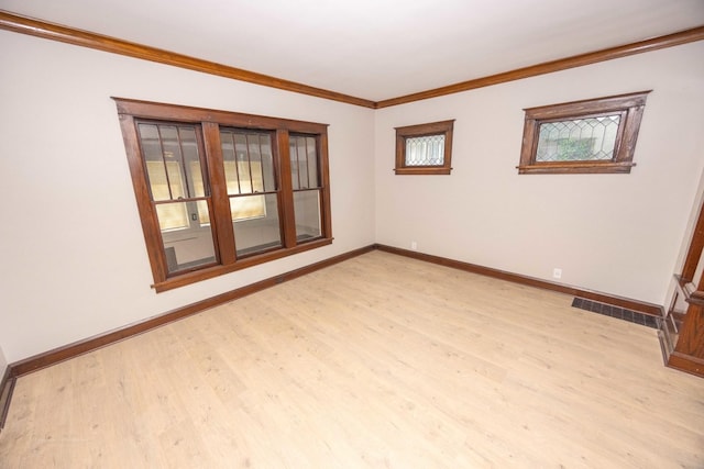empty room featuring baseboards, light wood finished floors, and crown molding