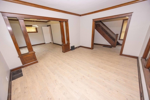 unfurnished room with light wood-type flooring, ornamental molding, stairway, and baseboards