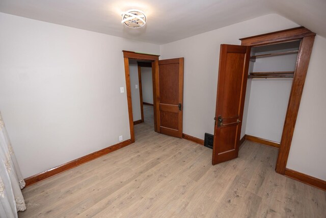 unfurnished bedroom featuring light wood finished floors, baseboards, and a closet