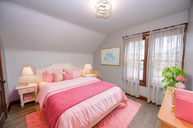 bedroom featuring lofted ceiling, wood finished floors, and baseboards