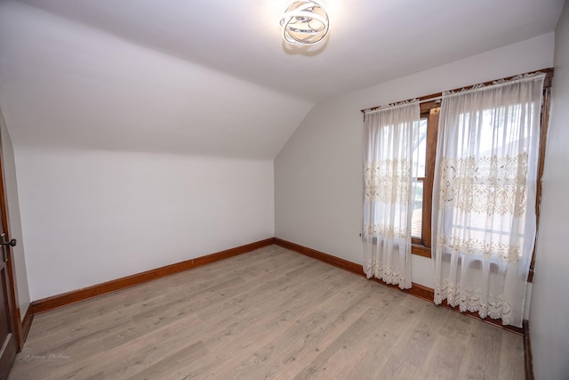 additional living space featuring baseboards, lofted ceiling, and light wood-type flooring