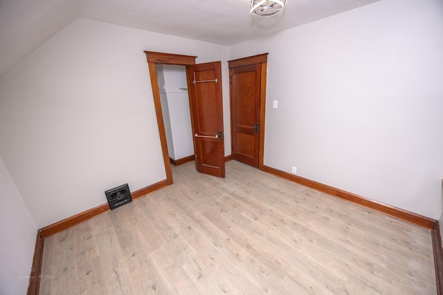 unfurnished bedroom with light wood-type flooring, baseboards, and vaulted ceiling