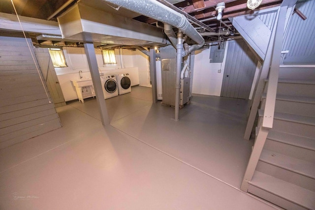 unfinished basement featuring washer and dryer, heating unit, and electric panel
