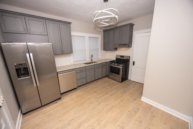 kitchen featuring stainless steel appliances, a sink, light wood-style floors, a chandelier, and under cabinet range hood