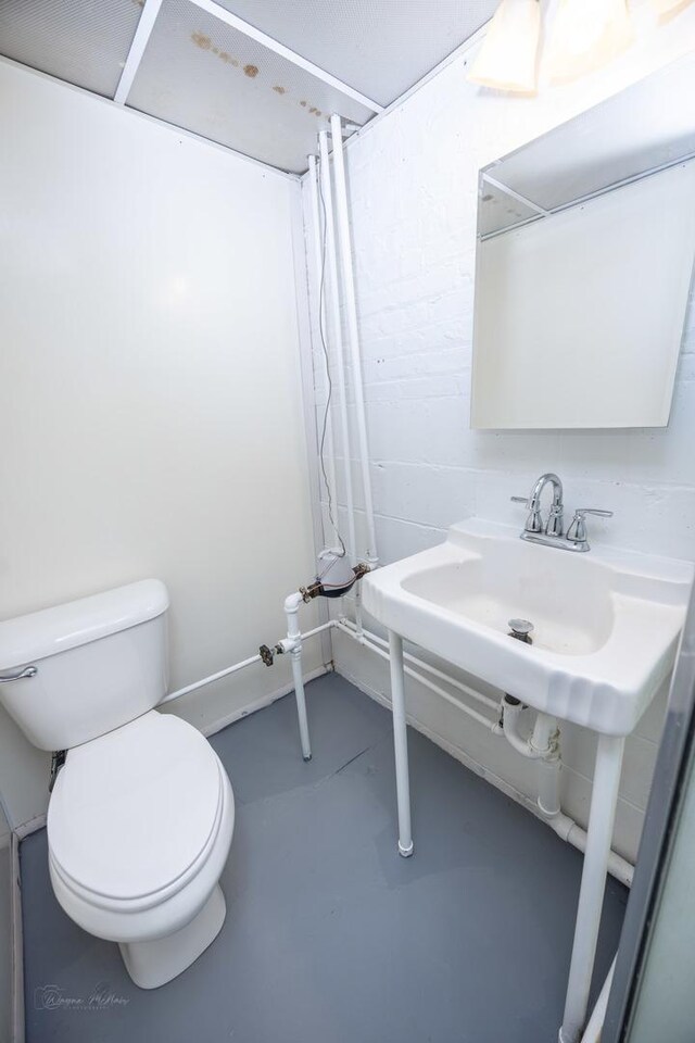 bathroom with concrete flooring, toilet, and a shower with curtain