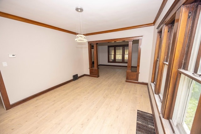 empty room featuring ornamental molding, light wood finished floors, and baseboards