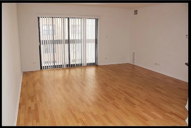 unfurnished room with healthy amount of natural light, light wood-type flooring, ornamental molding, and baseboards