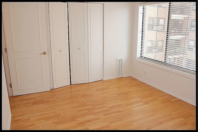 unfurnished bedroom with light wood-style flooring, a closet, and baseboards