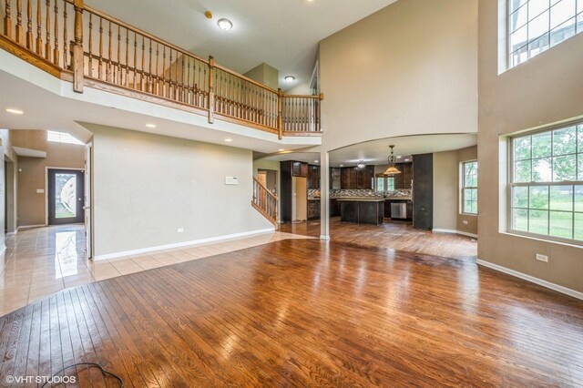 3140 Juniper Ct, Lynwood, IL 60411 - unfurnished living room with hardwood / wood-style floors, a towering ceiling, baseboards, and stairway