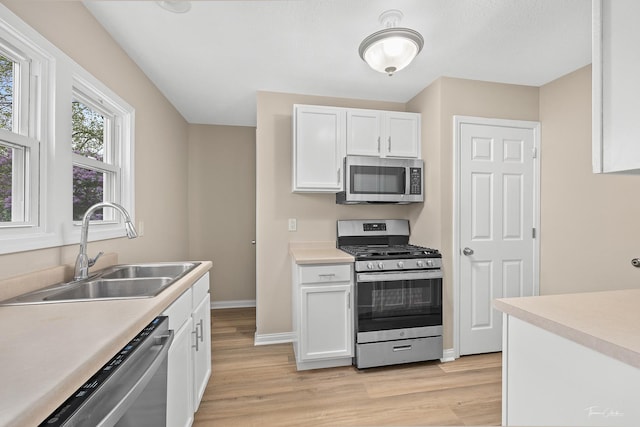 436 S Mckinley Ave, Kankakee, IL 60901 - kitchen featuring appliances with stainless steel finishes, a sink, white cabinets, light wood-style flooring, and baseboards