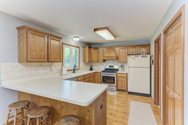 kitchen featuring appliances with stainless steel finishes, premium range hood, a peninsula, a sink, and tasteful backsplash
