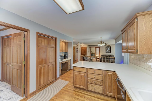 kitchen with light wood-style flooring, dishwasher, a peninsula, and light countertops