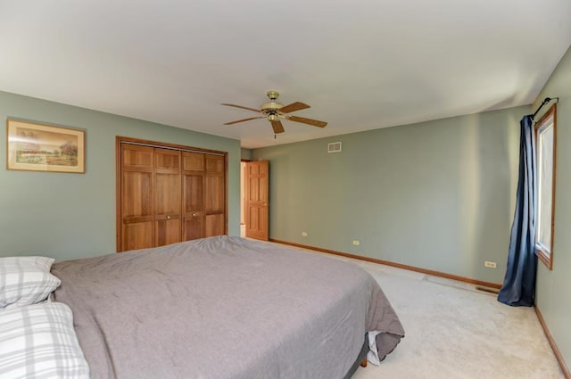 bedroom featuring baseboards, a closet, light colored carpet, and a ceiling fan
