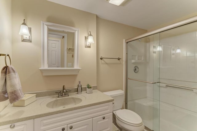 full bathroom featuring a stall shower, toilet, and vanity