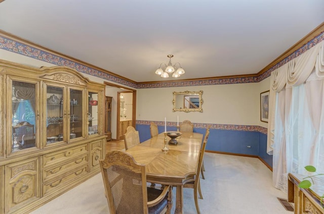 dining space with light carpet, a chandelier, wainscoting, and ornamental molding