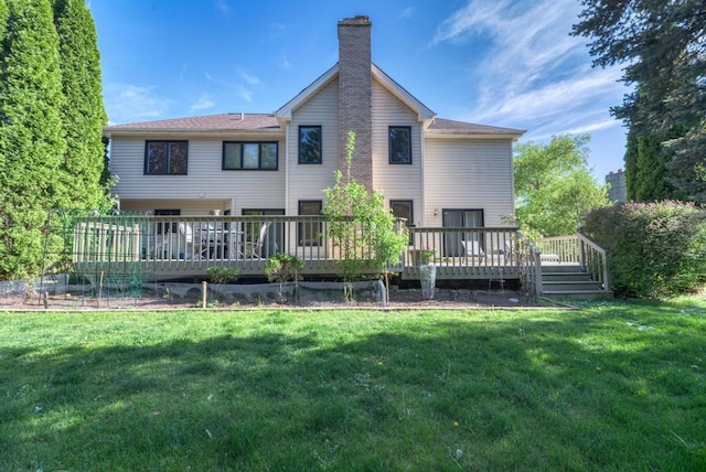 rear view of property featuring a chimney, a lawn, and a wooden deck