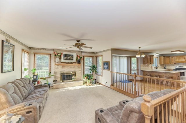 living room with ceiling fan, light colored carpet, a fireplace, and baseboards