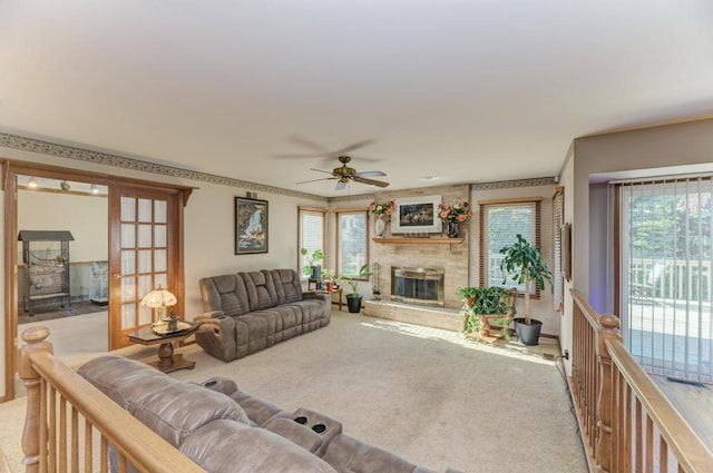 living area featuring light colored carpet, a brick fireplace, ceiling fan, and plenty of natural light